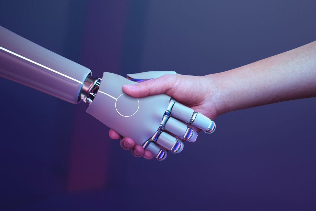 A robot shakes hands with a human.